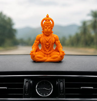 Orange Hanuman Ji idol seated in meditation on a car dashboard