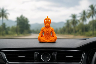 Hanuman Ji idol on a car dashboard with an open road ahead