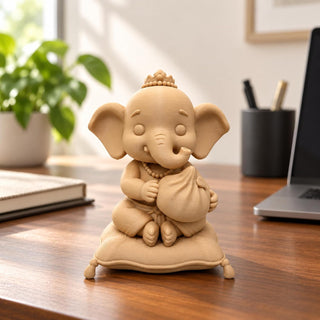 Mini Ganesha idol on a wooden office desk beside a laptop and plant