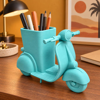 Scooter pencil holder on a wooden desk beside a lamp holding pens and pencils