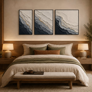 Framed abstract relief wall art above a bed in a warm bedroom
