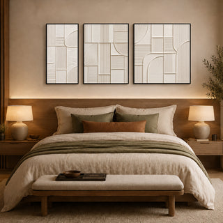 Framed abstract relief wall art above a bed in a warm bedroom