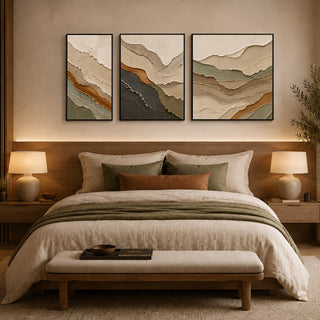 Framed abstract relief wall art above a bed in a warm bedroom